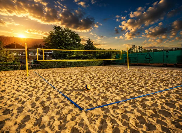 Beachvolleyball-Feld mit gelbem Netz und Ball im Sand, Blick über die Anlage